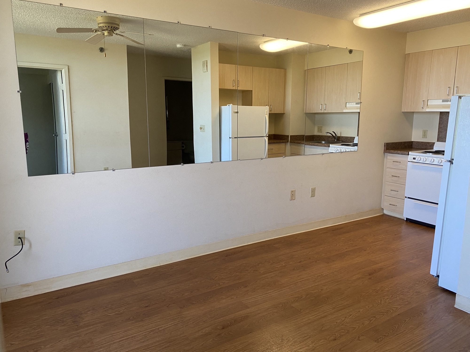 an empty living room with a kitchen in the background